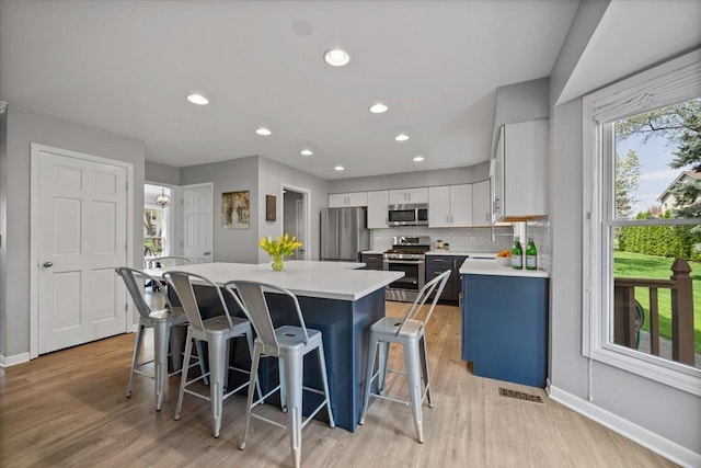 kitchen with a breakfast bar, baseboards, a center island, light countertops, and stainless steel appliances
