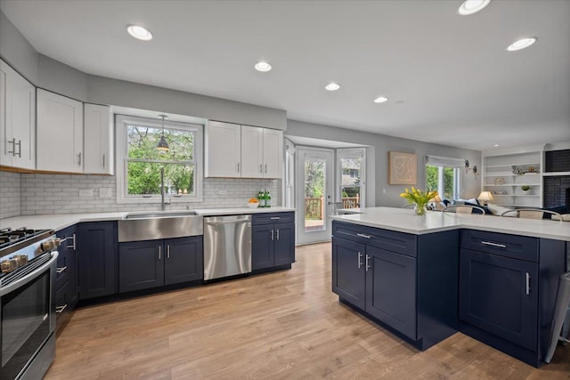 kitchen with appliances with stainless steel finishes, a sink, light countertops, white cabinets, and open floor plan