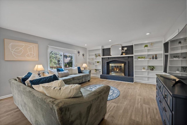 living area with light wood-type flooring, recessed lighting, baseboards, and a fireplace
