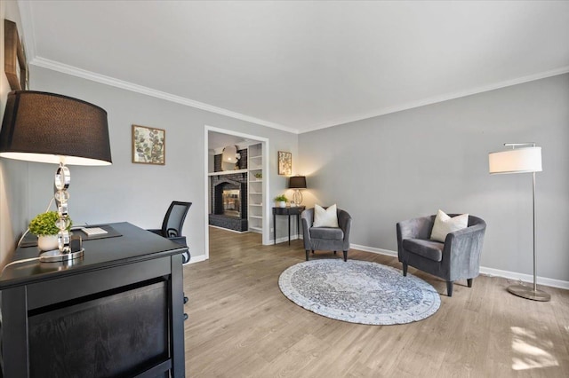 office space featuring crown molding, baseboards, a brick fireplace, and light wood-type flooring