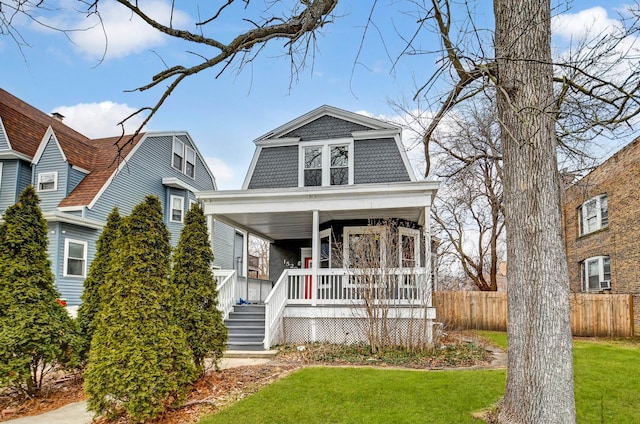 view of front of home with a front lawn, a gambrel roof, a porch, and fence
