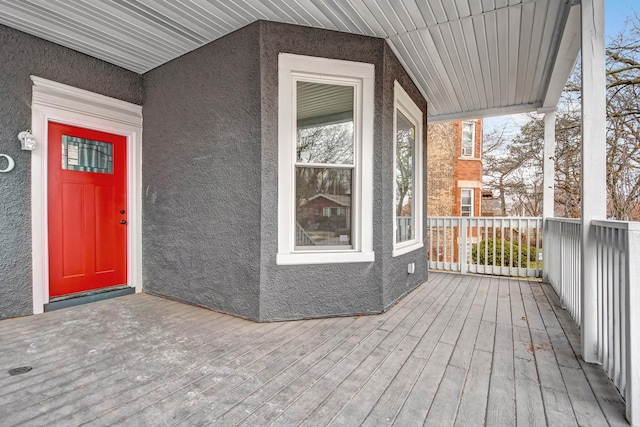 entrance to property featuring a wooden deck and stucco siding