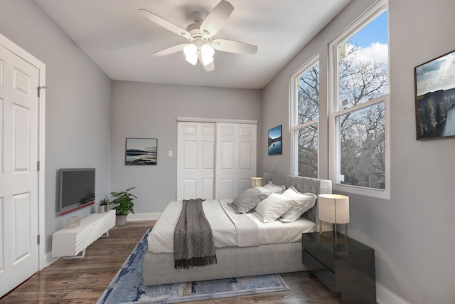 bedroom featuring baseboards, wood finished floors, a closet, and ceiling fan