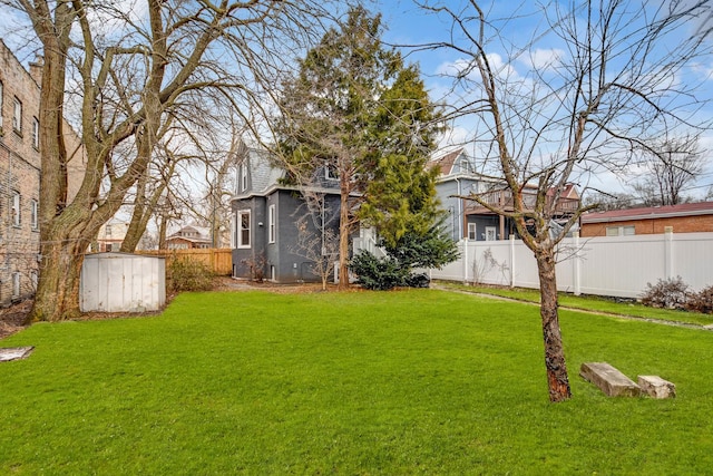 view of yard featuring a fenced backyard, a sunroom, an outbuilding, and a storage unit
