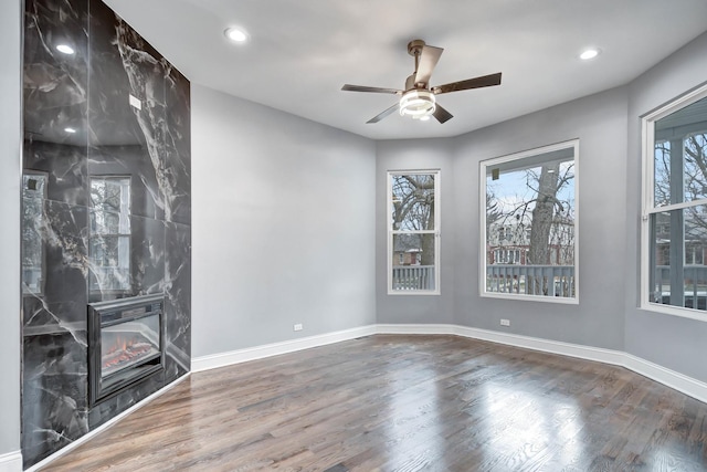 unfurnished living room with baseboards, recessed lighting, wood finished floors, ceiling fan, and a high end fireplace