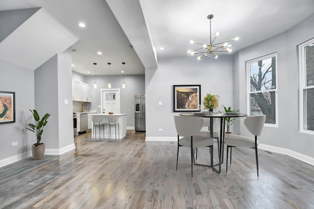 dining room with a chandelier, wood finished floors, baseboards, and recessed lighting