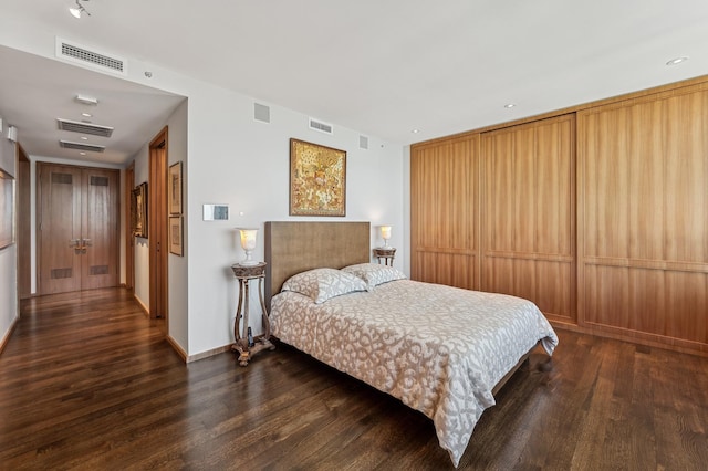 bedroom featuring baseboards, wood finished floors, and visible vents