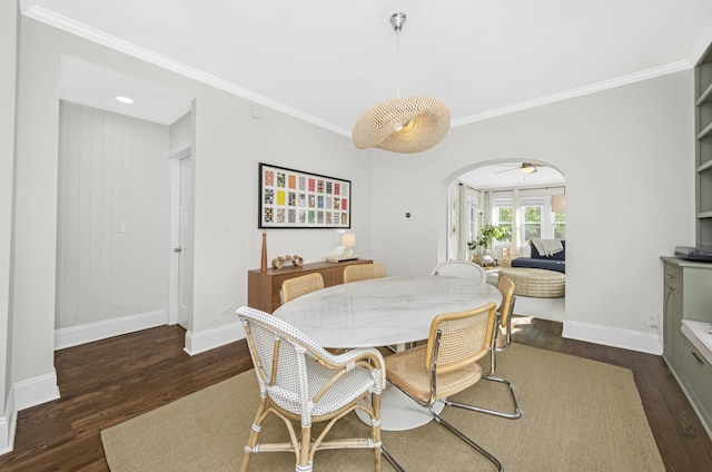 dining space with baseboards, ornamental molding, dark wood finished floors, and arched walkways