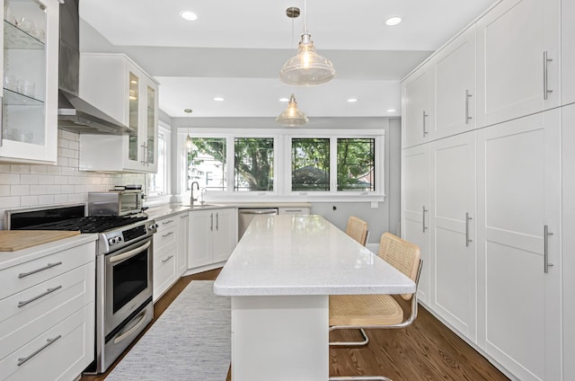 kitchen with appliances with stainless steel finishes, dark wood-style flooring, plenty of natural light, and wall chimney exhaust hood