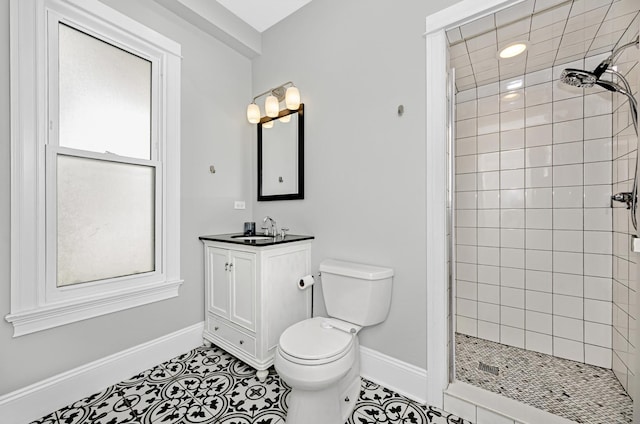 full bath with tiled shower, vanity, tile patterned floors, toilet, and baseboards