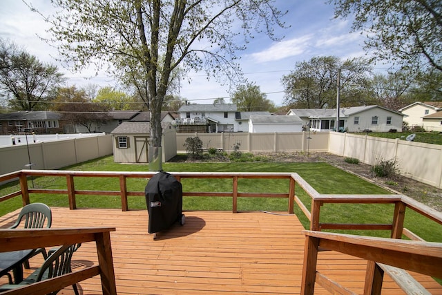 wooden deck with a residential view, an outdoor structure, a fenced backyard, a lawn, and a storage unit