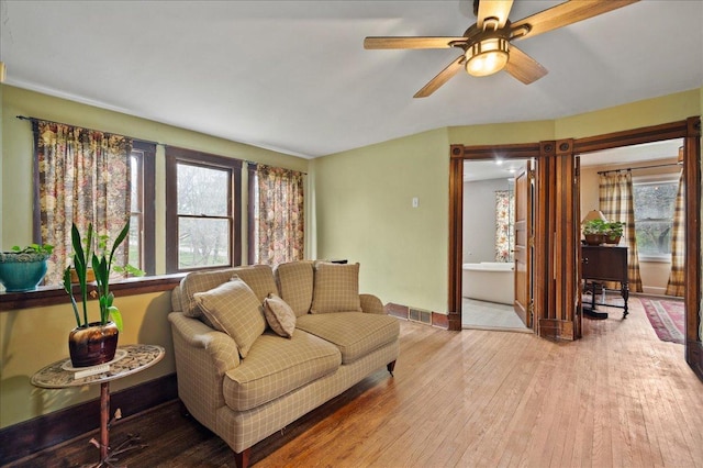 living room with visible vents, hardwood / wood-style flooring, baseboards, and ceiling fan
