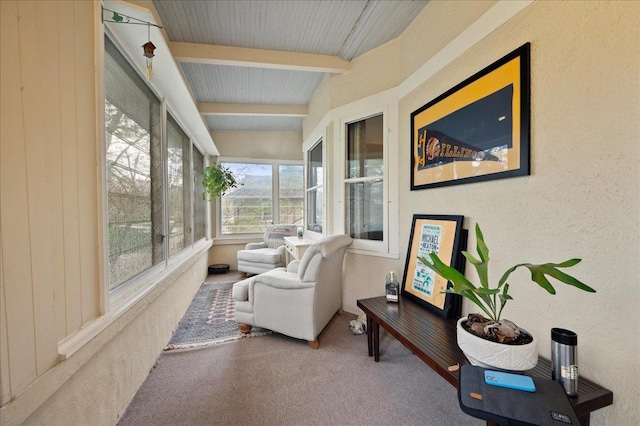 sunroom featuring beamed ceiling, a textured wall, and carpet floors
