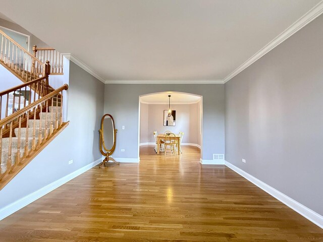 661 Bluebonnett Dr, Aurora, IL 60505 - empty room featuring arched walkways, wood finished floors, stairs, baseboards, and ornamental molding