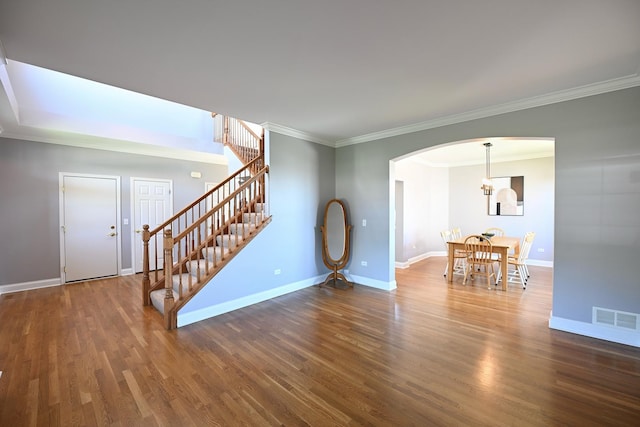 661 Bluebonnett Dr, Aurora, IL 60505 - unfurnished living room featuring arched walkways, stairway, crown molding, wood finished floors, and baseboards