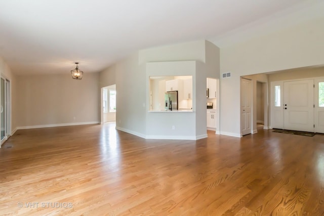 2509 Oak Trails Dr, Aurora, IL 60506 - unfurnished living room featuring lofted ceiling, light wood-style flooring, and a chandelier