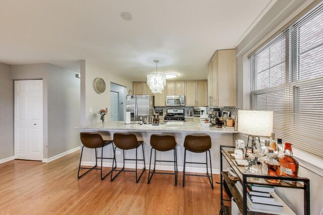 1473 N Larrabee St Unit A, Chicago, IL 60610 - kitchen with stainless steel appliances, a peninsula, light wood-style flooring, and tasteful backsplash