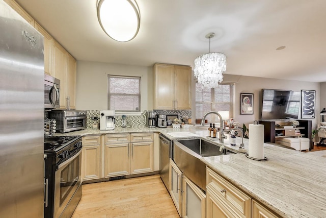 1473 N Larrabee St Unit A, Chicago, IL 60610 - kitchen with stainless steel appliances, decorative backsplash, light stone counters, light wood-type flooring, and a chandelier