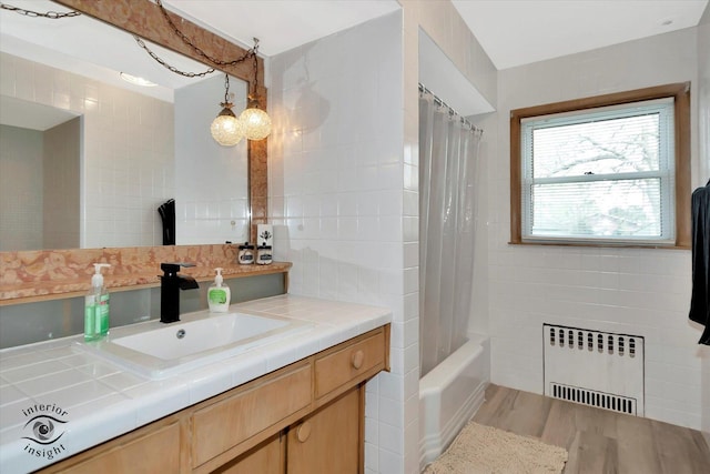 full bathroom with vanity, tile walls, radiator heating unit, and wood finished floors