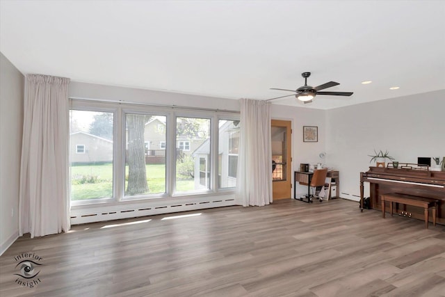 living area with light wood-style floors, recessed lighting, ceiling fan, and a baseboard heating unit