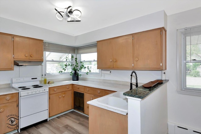 kitchen featuring a peninsula, a baseboard heating unit, under cabinet range hood, white range with electric stovetop, and light wood finished floors