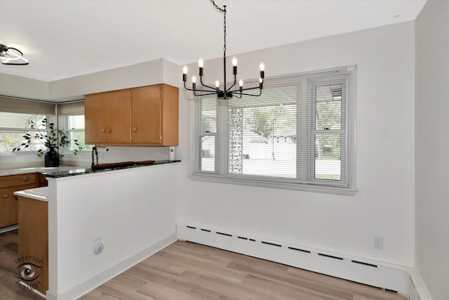 unfurnished dining area featuring light wood-type flooring, baseboards, a baseboard heating unit, and a chandelier