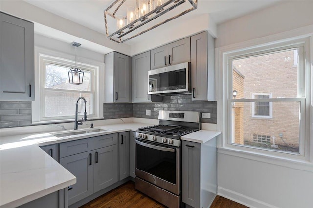 7241 N Kilpatrick Ave, Lincolnwood, IL 60712 - kitchen with a sink, decorative backsplash, gray cabinetry, light countertops, and appliances with stainless steel finishes