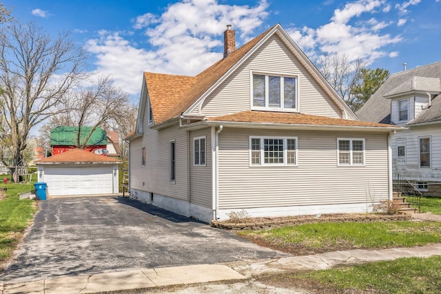 view of home's exterior featuring a chimney, roof with shingles, an outbuilding, and a garage