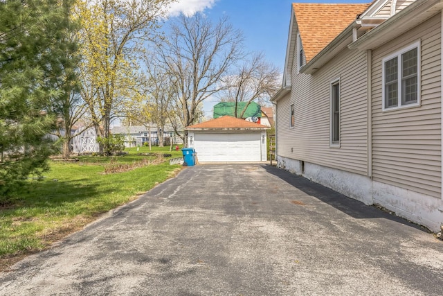 view of property exterior with roof with shingles, an outbuilding, a yard, and a detached garage