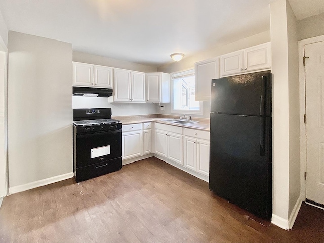 kitchen with white cabinets, a sink, under cabinet range hood, and black appliances