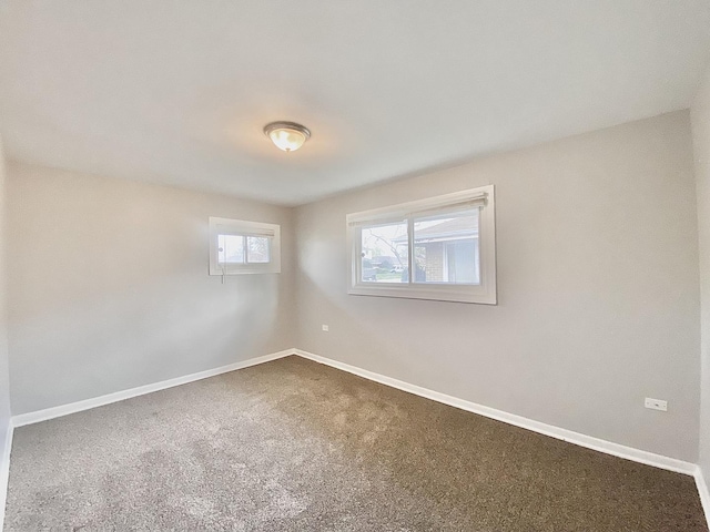 empty room with dark carpet and baseboards