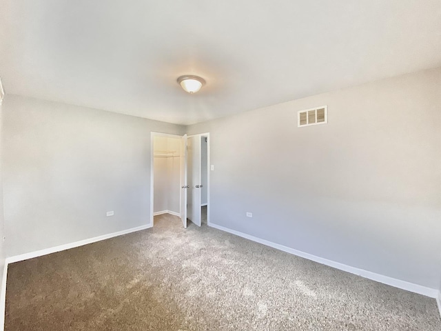 empty room featuring carpet floors, visible vents, and baseboards