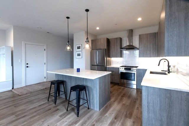 117 S Bell Ave Unit 4S, Chicago, IL 60612 - kitchen with a breakfast bar area, a sink, stainless steel appliances, modern cabinets, and wall chimney range hood