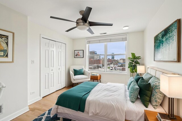 bedroom featuring visible vents, a closet, baseboards, ceiling fan, and light wood-style flooring
