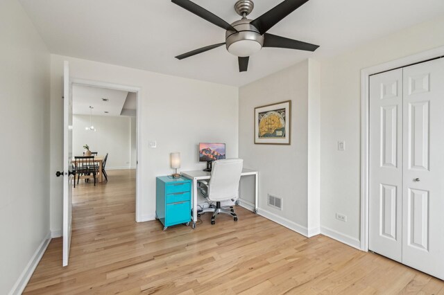 home office featuring light wood-style floors, a ceiling fan, and visible vents