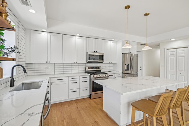 kitchen featuring appliances with stainless steel finishes, a sink, recessed lighting, a kitchen bar, and backsplash