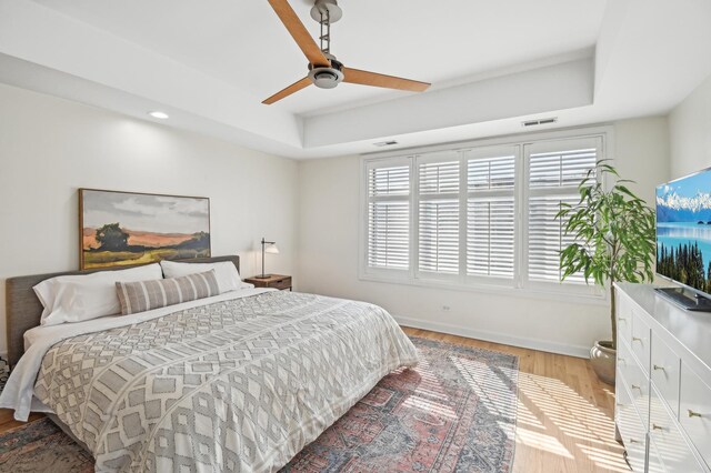 bedroom with visible vents, a raised ceiling, baseboards, and multiple windows