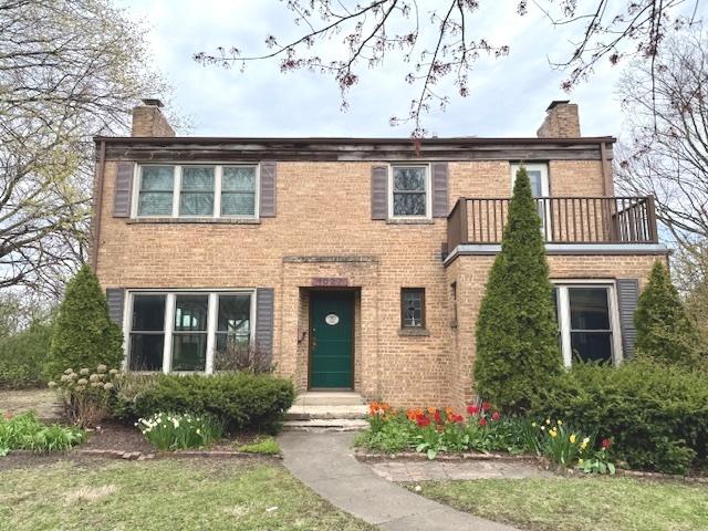 view of front of home with a chimney, brick siding, a balcony, and entry steps