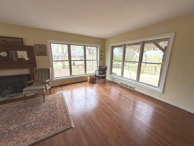 unfurnished room featuring baseboards, wood finished floors, visible vents, and a fireplace