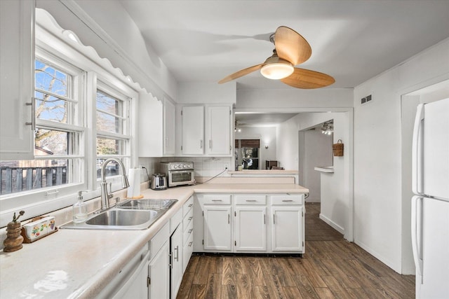 kitchen with a sink, light countertops, white cabinets, dark wood-style flooring, and freestanding refrigerator