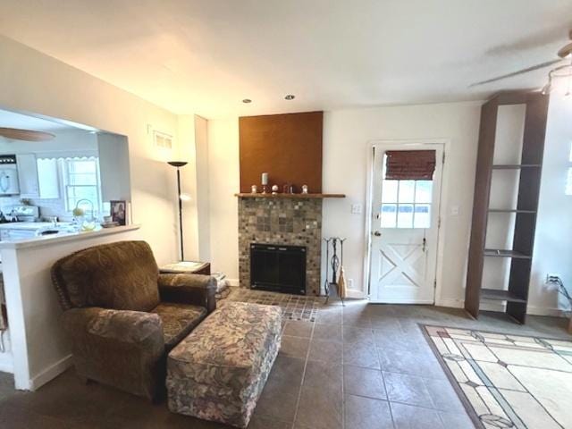 tiled living room featuring a ceiling fan, baseboards, and a fireplace