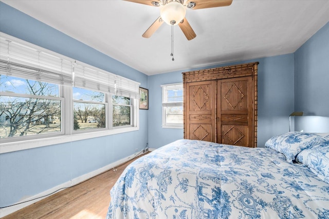 bedroom featuring light wood finished floors, baseboards, and a ceiling fan