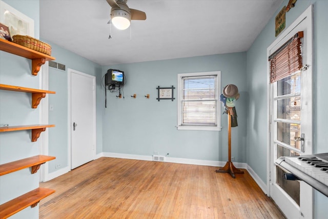 spare room featuring baseboards, a ceiling fan, visible vents, and light wood-style flooring