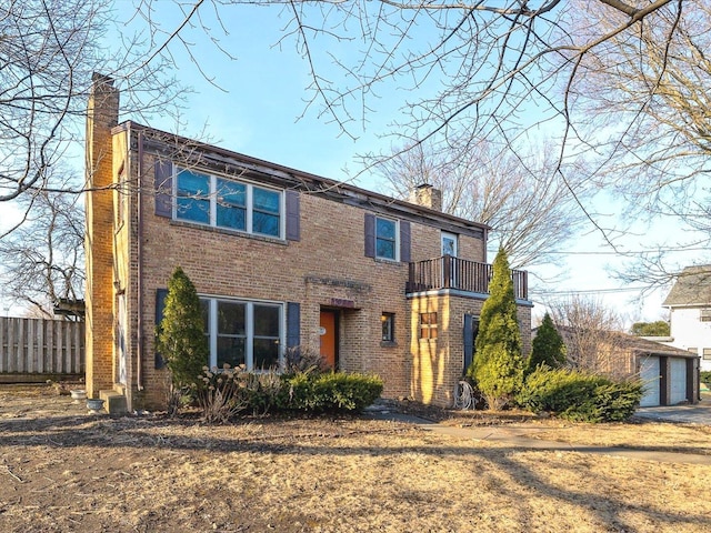 view of front of home with a chimney, brick siding, fence, and a balcony