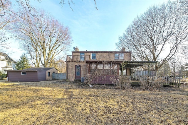 back of house featuring an outbuilding, a chimney, fence, brick siding, and a deck