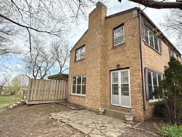 rear view of property with a chimney, brick siding, and entry steps