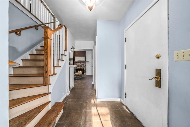 entrance foyer featuring dark tile patterned floors, baseboards, and stairs