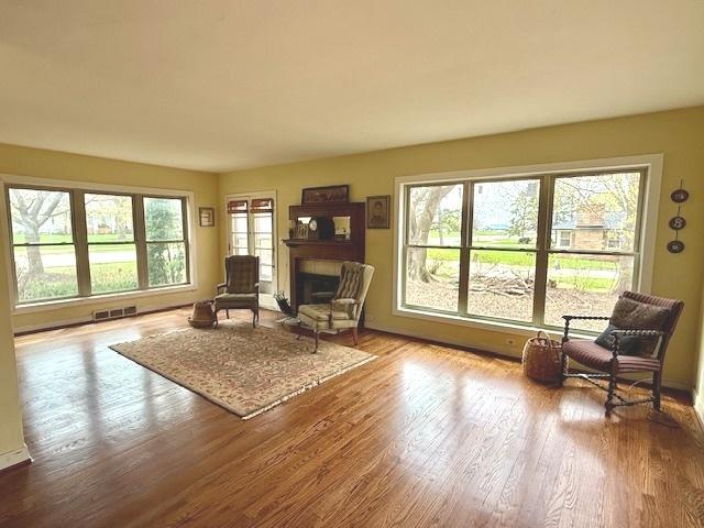 living area with a healthy amount of sunlight, wood finished floors, visible vents, and a fireplace