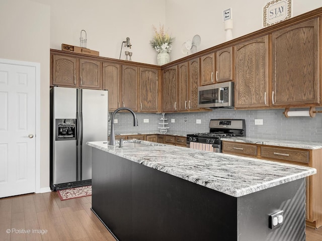 1683 Briarheath Dr, Aurora, IL 60505 - kitchen featuring light stone counters, a sink, stainless steel appliances, backsplash, and a center island with sink