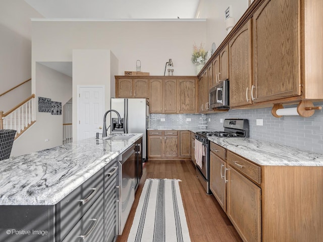 1683 Briarheath Dr, Aurora, IL 60505 - kitchen with a kitchen island with sink, appliances with stainless steel finishes, tasteful backsplash, light stone counters, and dark wood-type flooring